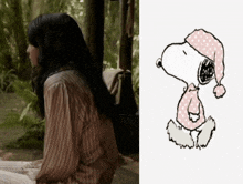 a woman in a striped shirt sits next to a drawing of snoopy wearing a pink polka dot hat