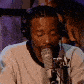 a man wearing headphones is singing into a microphone in a studio .