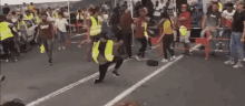 a man in a yellow vest is kneeling down in front of a crowd of people .
