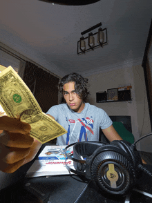 a man holding a dollar bill in front of a headphones