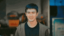 a man with a black shirt and a grey jacket smiles for the camera