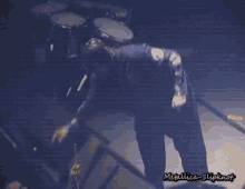 a man in a black jacket is standing on a stage with a microphone .