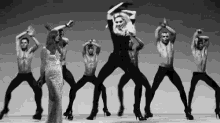 a woman in a dress is dancing with a group of men in high heels .