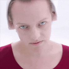 a close up of a woman 's face with blue eyes and a red top .