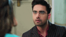 a man in a suit and glasses is looking at a woman in a room .