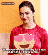a woman wearing a red shirt with a heart shaped face on it is waiting for a text .