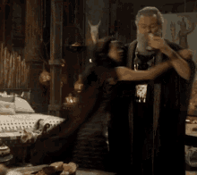a man with a beard is hugging a woman in a room with a bed .