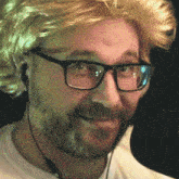 a man wearing a wig and glasses is smiling in front of a microphone