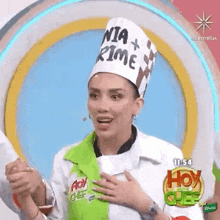a woman wearing a chef 's hat is standing on a stage with her hands on her chest .