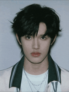 a young man wearing a white shirt and a necklace