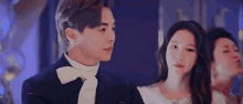a man and a woman are standing next to each other in a room and looking at each other .