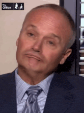 a man in a suit and tie with the office logo on the bottom