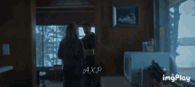 a man and a woman are standing in a room with the word axp on the bottom left