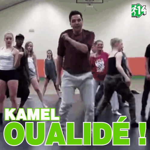 a group of people are dancing in a gym with the words kamel oualide written in green