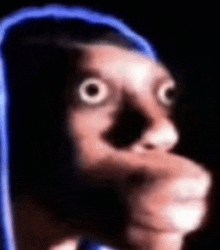 a blurry picture of a person 's face with big eyes and a blue hoodie .