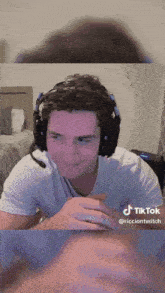 a man wearing headphones and a white shirt has a tiktok icon on the bottom right