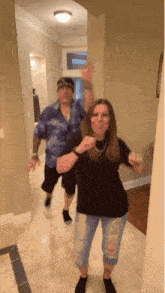 a man and woman are dancing in a hallway and the woman is pointing at the camera