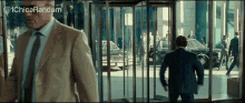 a man in a suit is walking through a revolving door