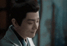 a close up of a man 's face with his eyes closed and a bun on his head .