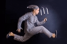 a man in pajamas is jumping in the air with candles in his hand .