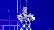 a man with his arms outstretched is wearing a plaid vest and glasses