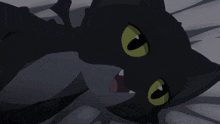 a black cat with yellow eyes laying on a bed