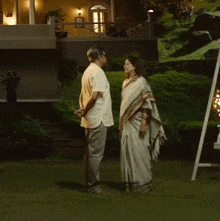 a man and a woman standing in front of a house holding hands