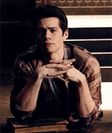 a man is sitting at a table with his hands folded and looking at the camera .