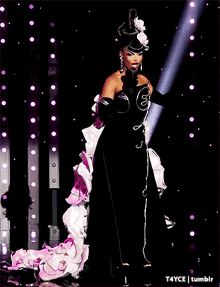 a woman in a black and white dress is singing into a microphone on a stage