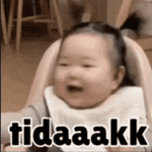 a baby is sitting in a high chair with a bib on and smiling .