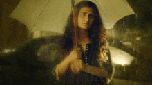 a woman holding an umbrella in the rain at night