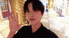a young man in a black shirt is waving his hand at the camera