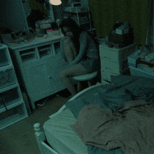 a woman is sitting on a stool in a bedroom