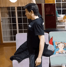 a man in a black t-shirt is sitting on a couch