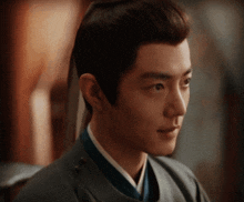 a close up of a man 's face with a ponytail and a blue shirt .