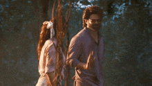 a man and a woman are standing next to each other in a forest