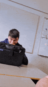 a man is holding a cell phone in front of a white board that says 00