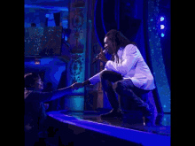 a man with dreadlocks is singing into a microphone while wearing a white suit