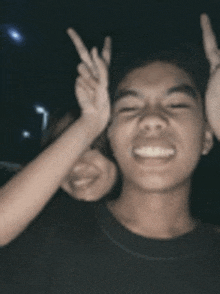 a man and woman are making a peace sign with their hands .