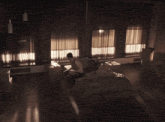 a man is laying on a bed in a dark room with a lot of windows