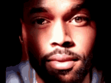 a close up of a man 's face with a beard in a dark room