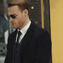 a man in a suit and tie is wearing sunglasses and a vest .