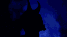 a statue of a devil with horns and teeth against a blue background