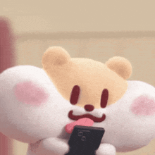 a stuffed animal is holding a cell phone with its tongue out .