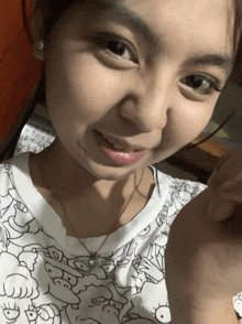 a close up of a woman 's face with a white shirt with a cartoon pattern on it