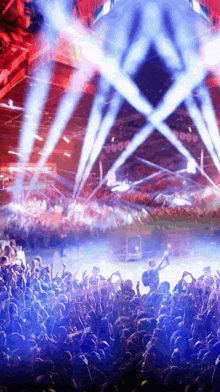 a crowd of people at a concert with blue and red lights coming from the stage