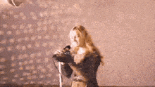 a woman singing into a microphone with her arms outstretched .