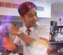a man in a suit and tie is dancing in a kitchen with bottles of alcohol in the background .