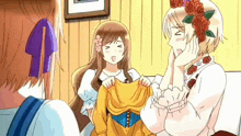 a man and two women are standing next to each other in a room . one of the women is wearing a yellow dress .