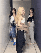 three women are standing next to each other in a hallway with one wearing a white tank top
